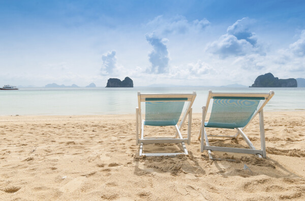 放在海边沙滩上的两把太阳椅图片