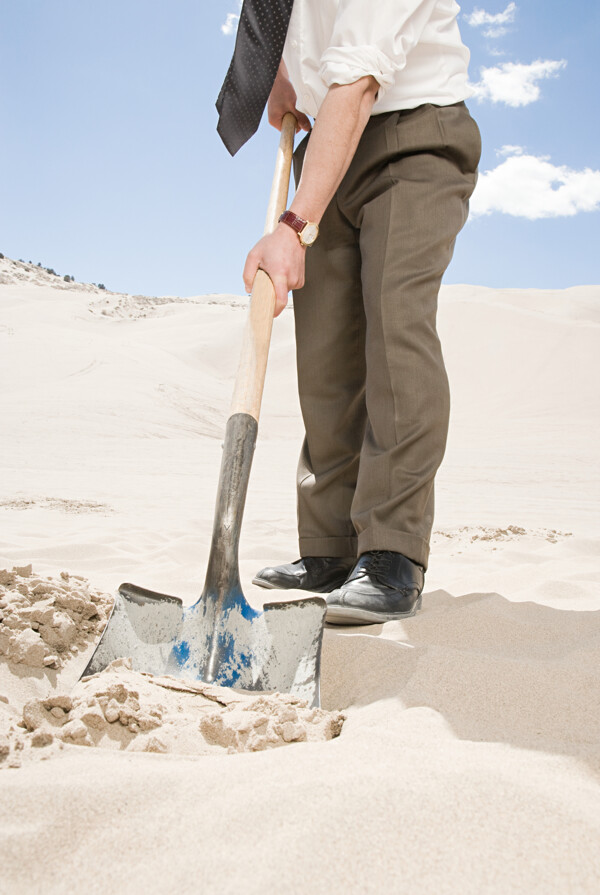 沙漠中铲沙子的男人图片