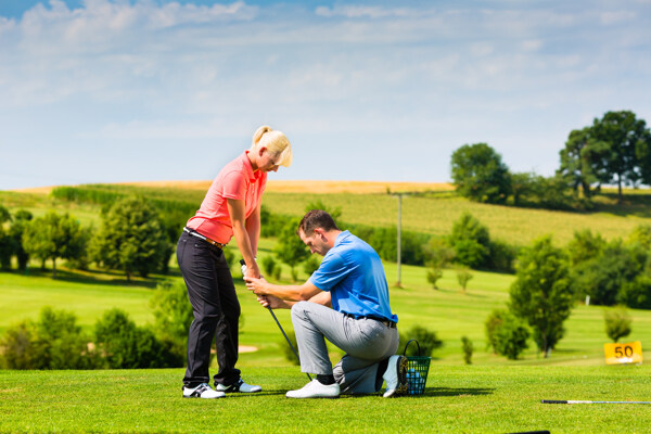 草地外国男人教外国女人打高尔夫球