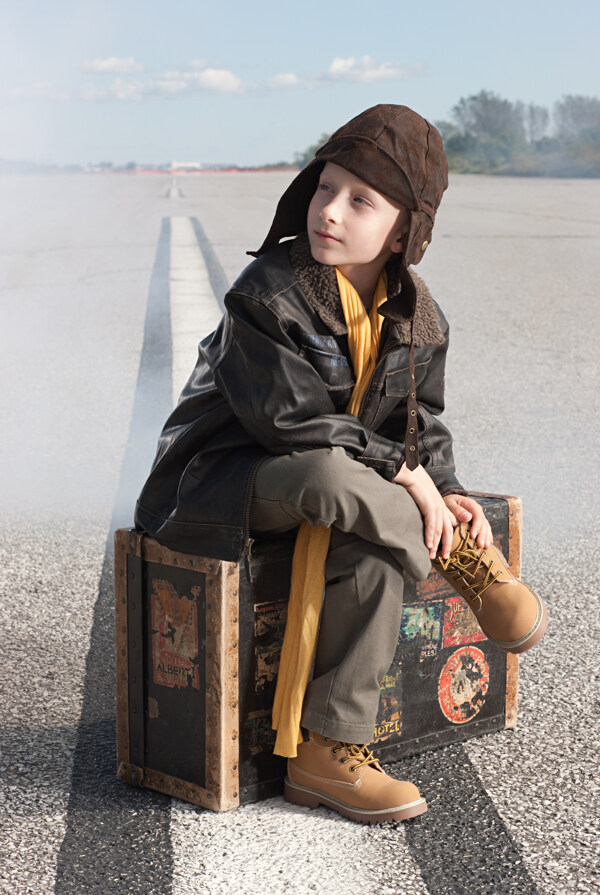 戴帽子男孩坐着行李箱上的男孩图片
