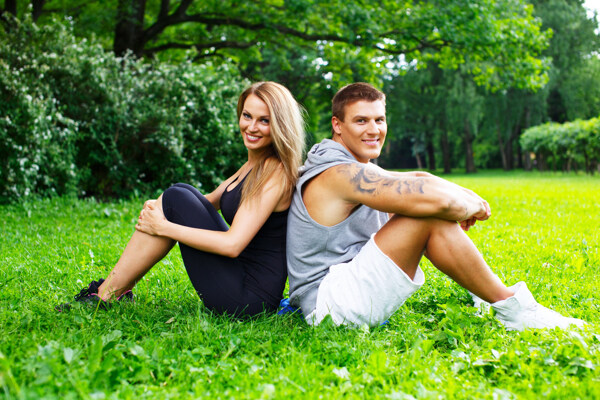 坐在草地上背靠背的情侣图片
