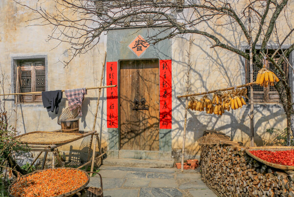 門前貼著紅色的春聯(lián)周圍晾曬著農(nóng)作物傳統(tǒng)的中國農(nóng)村房屋