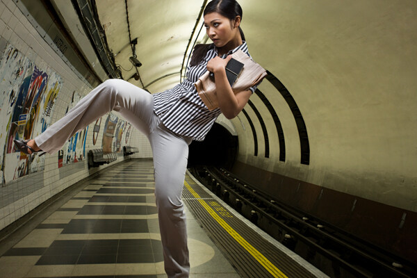 在地铁站台踢腿运动的时尚美女图片
