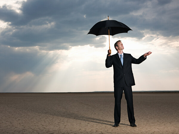站在沙漠中拿着伞等待下雨的外国男人图片