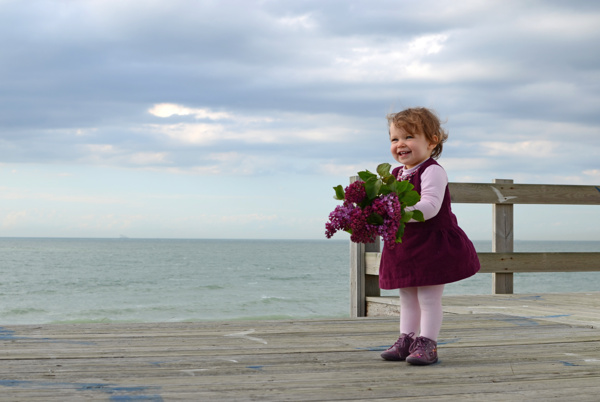站在海边拿着鲜花的外国小女孩